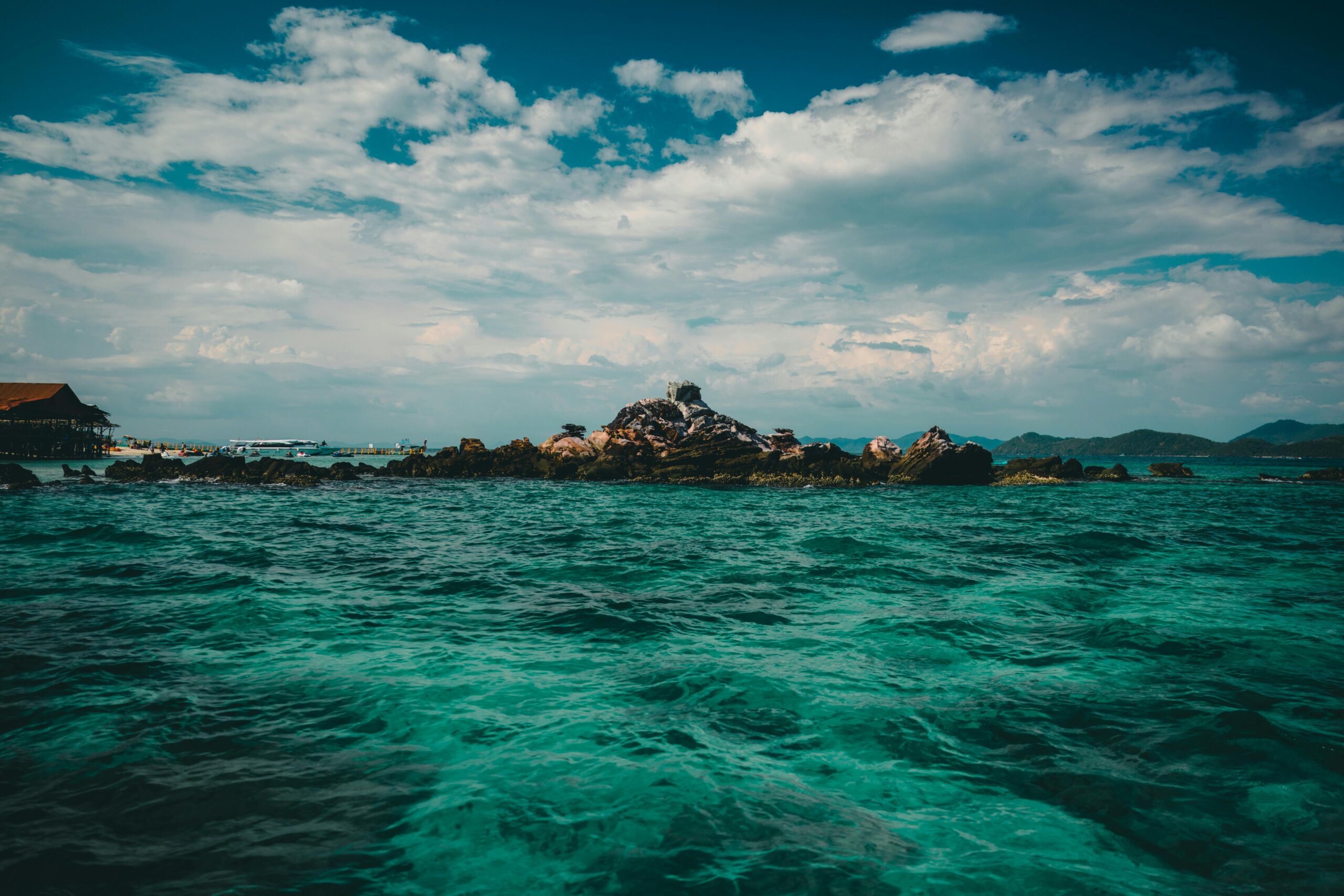 Breathtaking view of a rocky island in the turquoise sea of Phuket, Thailand under a dramatic sky.